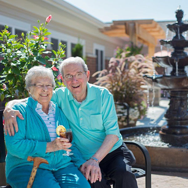 Elderly couple sitting on bench in front of a fountain